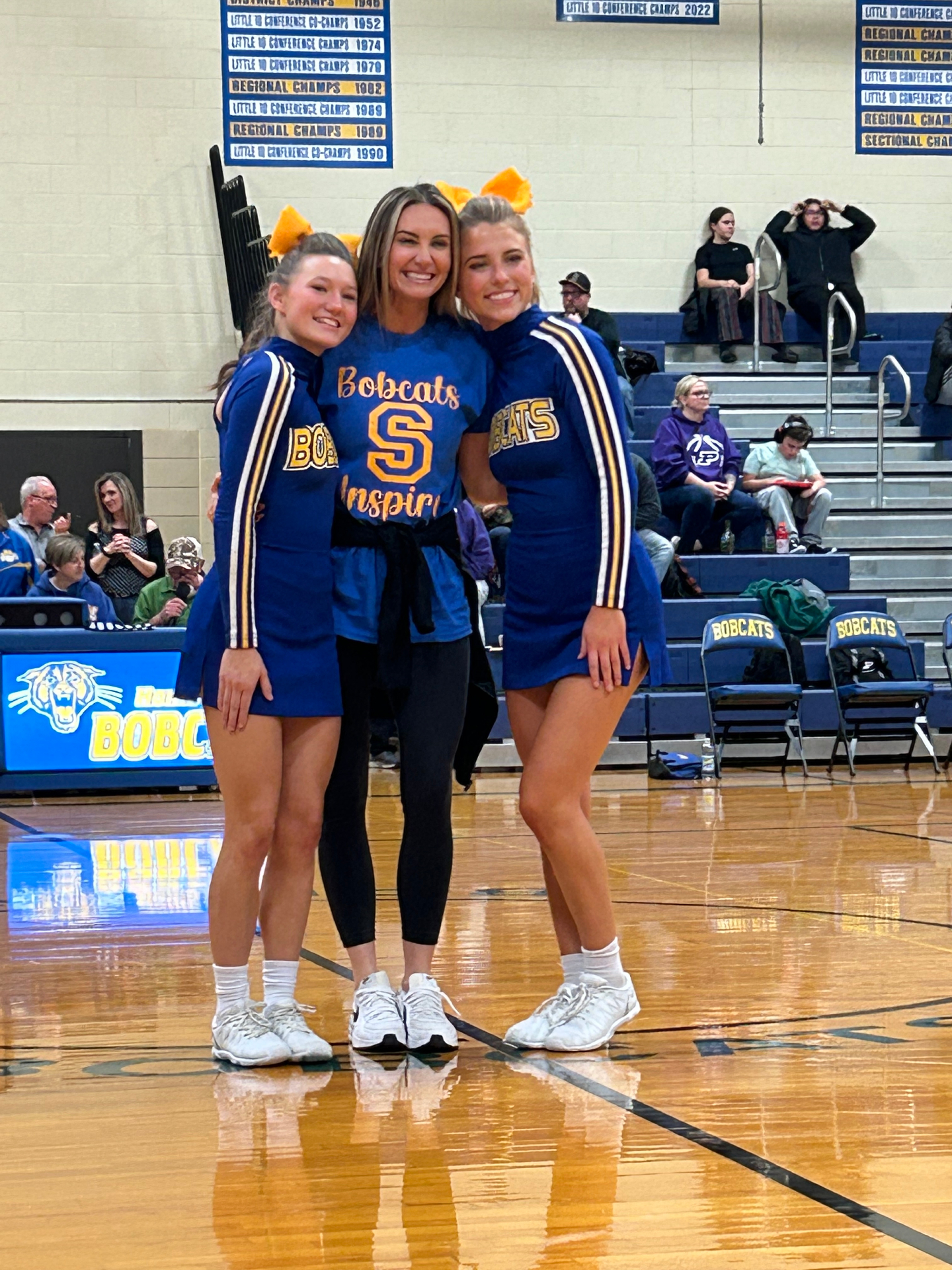 Laci coaching two Bobcats cheerleaders on the gym floor